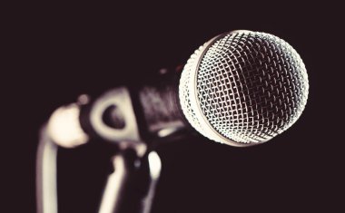 Kasvetli bir arkaplanda ses mikrofonu. Canlı müzik, ses ekipmanları. Karaoke konseri, şarkı söyleme. Karaokede şarkıcı, mikrofonlar. Mikrofon, mikrofon, karaoke, konser, ses müziği.