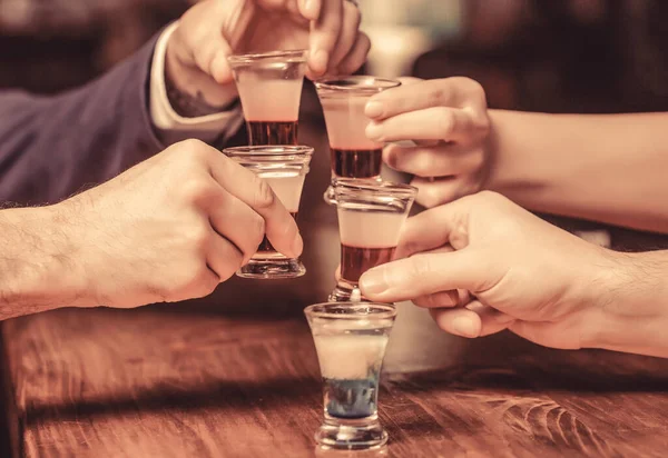 Group friends tequila shot glasses in bar. Male hands glasses of shot or liqueur. Friends drink shot or liqueur. Five glasses of alcohol.Tequila shots, vodka, whisky, rum.