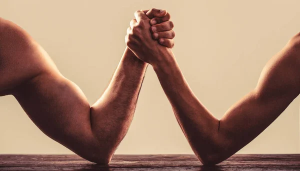 Two mans hands clasped arm wrestling, strong and weak, unequal match.