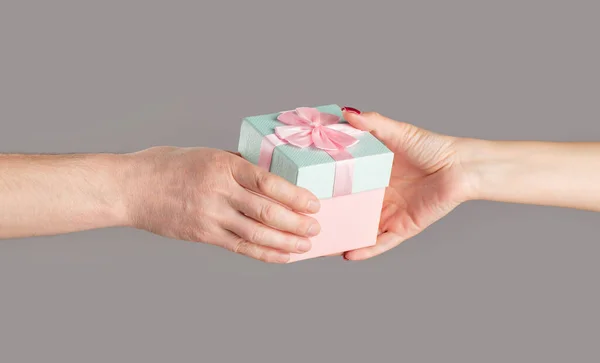 Gift box in hand, surprise and holiday concept. Man hands holding valentines day gift. Male and female hands holding pink gifts box. Girl gives a gift to man. Woman hands holding gift.