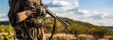 Silahlı bir erkek. Sırt çantası ve av silahı olan bir avcı. Avlanma silahı ve avlanma biçimi olan bir avcı. Adam avda şu an. Avcı adam. Av dönemi, sonbahar mevsimi..