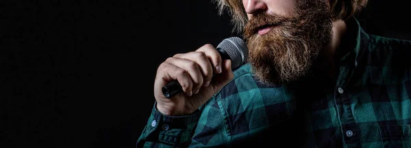 Bearded man in karaoke sings a song into a microphone. Male attends karaoke. Man with a beard holding a microphone and singing.