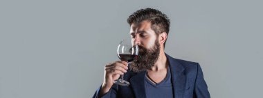 Man holding glass of champagne in hand. Man with a glass of red wine in his hands. Beard man, bearded, sommelier tasting red wine.