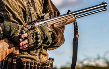 Male hunter in ready to hunt. Closeup. Hunter man. Hunting period. Male with a gun, rifle. Man is charging a hunting rifle.