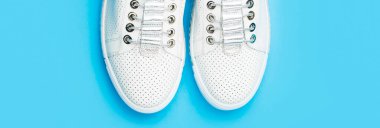 White shoes. Pair of white shoes on blue background. Overhead shot of running shoes. Close up, modern fashion shoes made of laces.