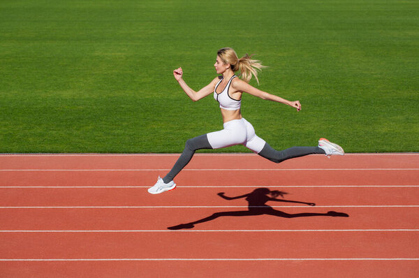 Woman running during. Sport backgrounds. Runner. Professional sportswoman during running training session. Woman running jump on stadium track. Sportswoman in sportswear jumping.
