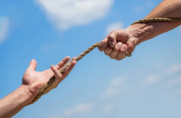 Rescue, help, helping gesture or hands. Conflict tug of war. Rope, cord. Hand holding a rope, climbing rope, strength and determination.