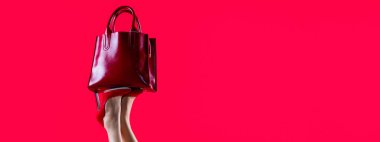 Stylish red female leather bag. Perfect female legs wearing high heels. Shapely legs, a girl in shoes high-heeled. Red glossy female leather bag.