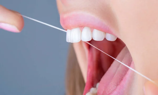 Teeths Flossing. Oral hygiene and health care. Smiling women use dental floss white healthy teeth. Dental flush - woman flossing teeth. Dental floss. Taking care of teeth. Healthy teeth concept.