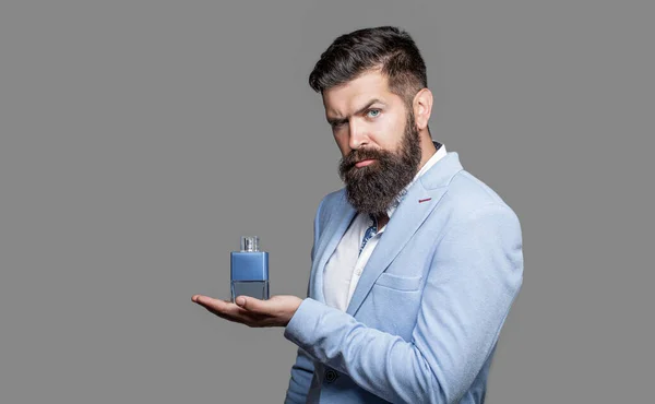 Perfume or cologne bottle and perfumery, cosmetics, scent cologne bottle, male holding cologne. Masculine perfume, bearded man in a suit. Masculine perfume, bearded man in a suit.