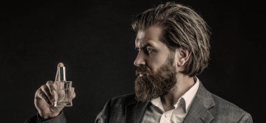 Perfume or cologne bottle and perfumery, cosmetics, scent cologne bottle, male holding cologne. Male holding up bottle of perfume. Man perfume, fragrance. Masculine perfume, bearded man in a suit.