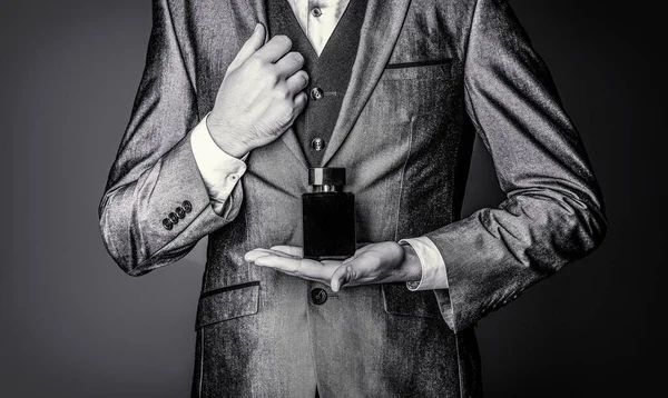 Men perfume in the hand on suit background. Fragrance smell. Black and white.