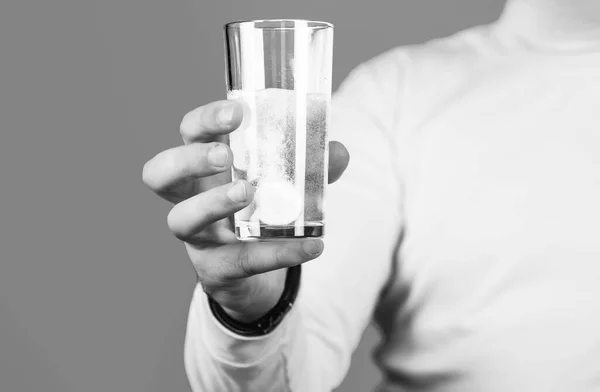 Close up of man holding a pill. Glass of water tablet. Glass with efervescent tablet in water with bubbles. Black and white.