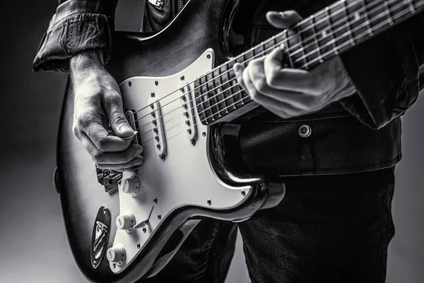 Music festival. Man playing guitar. Close up hand playing guitar. Musician playing guitar, live music. Black and white. Musical instrument. Electric guitar. Repetition of rock music band.