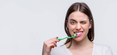 Elinde diş fırçası tutan güzel dişleri olan gülümseyen bir kadın. Diş sağlığı geçmişi. Elinde diş fırçası tutan gülümseyen sevimli bir kadının portresi..