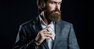 Erkek parfümü, takım elbiseli sakallı bir adam. Elinde parfüm şişesi tutan bir erkek. Parfüm, parfüm şişesi, parfüm, kozmetik, parfüm şişesi, erkek parfümü. Erkek parfümü, parfüm.