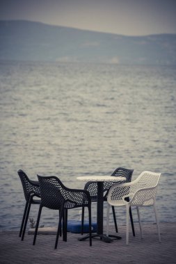 Açık bir terasta, göl kenarında boş sandalye ve masaların renkli görüntüsü.