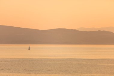Şafakta gölde yüzen bir teknenin görüntüsü..