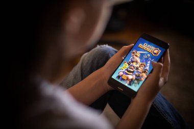 Bükreş, ROMANIA - 10 Mayıs 2021: Cep telefonuyla Clash Royale oyunu oynayan bir çocuğun resimli editör konsepti.
