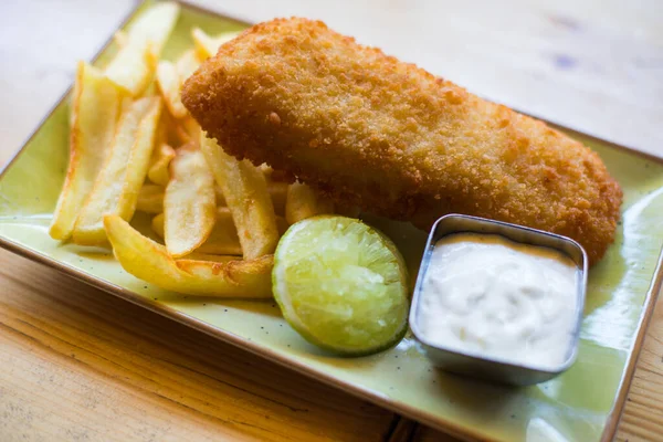 British Traditional Fish and chips with tartar sauce on a plate.