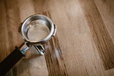 Kalıplı ahşap bir yüzey üzerinde fotokopi alanı olan bir espresso filtresinin genel görünümü.