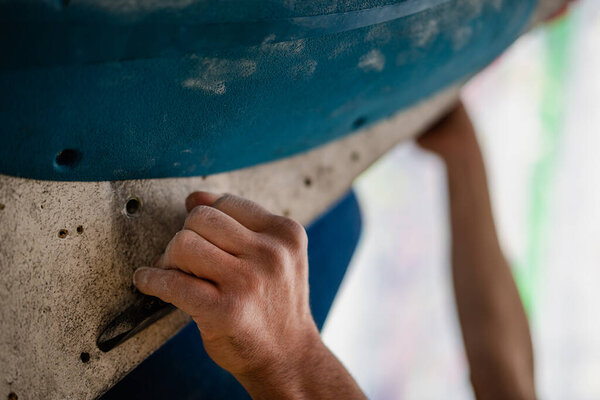 Крупный план мужской руки, размазанной магниевым порошком, хватающейся за стену в спортзале.