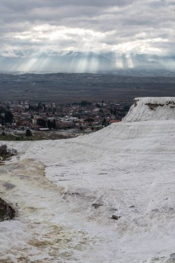 Dramatik güneş ışığı bulutları delip geçiyor ve destansı bir manzarayla dağlara çarpıyor..
