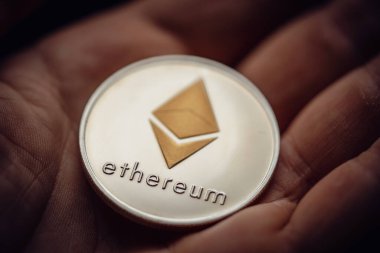 Gümüş bir Ethereum dijital kripto para birimini tutarken yakın çekim.
