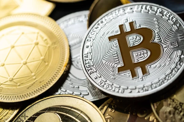 Bir yığın içinde gümüş bir Bitcoin 'in yakın plan çekimleri, diğer dijital kripto para birimleri arasında .