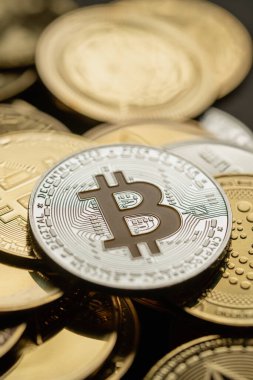 Bir yığın içinde gümüş bir Bitcoin 'in yakın plan çekimleri, diğer dijital kripto para birimleri arasında .