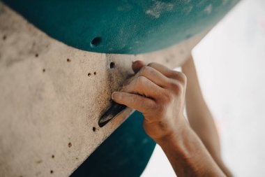 Spor salonunda magnezyum tozu sürüp tırmanma duvarına tutunan bir erkeğin yakın çekim görüntüsü..