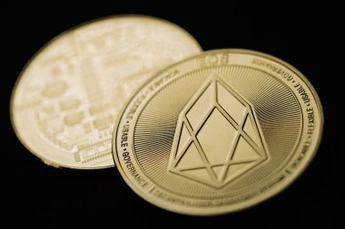 Close up shot of a golden EOS digital cryptocurrency, front and back.