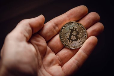 Gümüş bir bitcoin dijital kripto para tutarken yakın çekim.