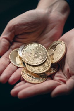 Elde gümüş ve altın tutarken yakın plan çekimde çeşitli dijital kripto para birimleri, üzerinde Bitcoin ile.