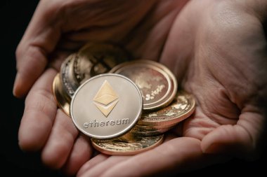 Ethereum 'un en üstte olduğu çeşitli dijital kripto para birimlerinin gümüş ve altını tutarken yakın plan çekimleri.