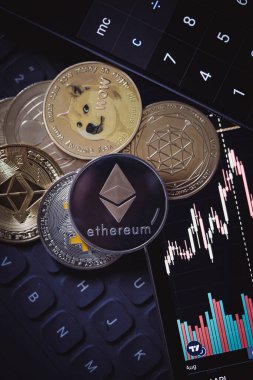 Stack or heap of gold various cryptocurrency near a monitor with candle stick graph chart and digital calculator. Bitcoin, Ethereum, Cardano, Litecoin.