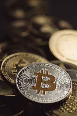 Bir yığın içinde gümüş bir Bitcoin 'in yakın plan çekimleri, diğer dijital kripto para birimleri arasında .