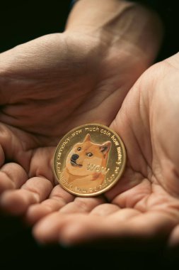 Altın bir Dogecoin dijital kripto para birimini elinde tutarken yakın çekim.