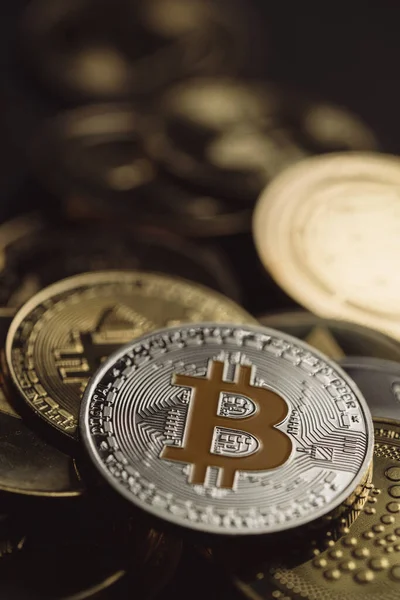 Bir yığın içinde gümüş bir Bitcoin 'in yakın plan çekimleri, diğer dijital kripto para birimleri arasında .