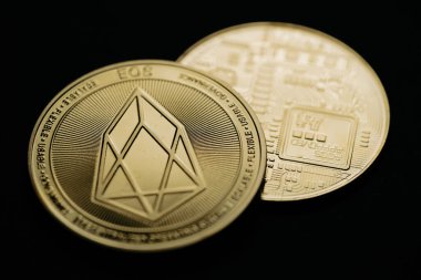 Close up shot of a golden EOS digital cryptocurrency, front and back.