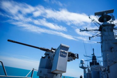 Color image of an automated machine gun on the deck of a military ship, at sea.