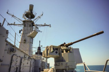 Color image of an automated machine gun on the deck of a military ship, at sea.