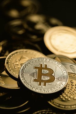 Bir yığın içinde gümüş bir Bitcoin 'in yakın plan çekimleri, diğer dijital kripto para birimleri arasında.