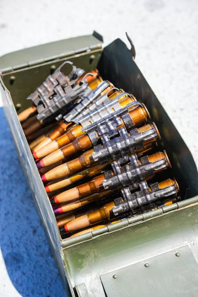 Close up shot of a machine gun belt loaded with cartridges, in an ammo box.