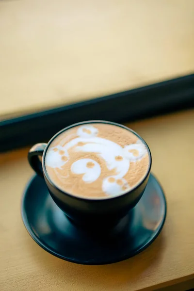 Hot cappuccino in a cup with a bear face shape on top.