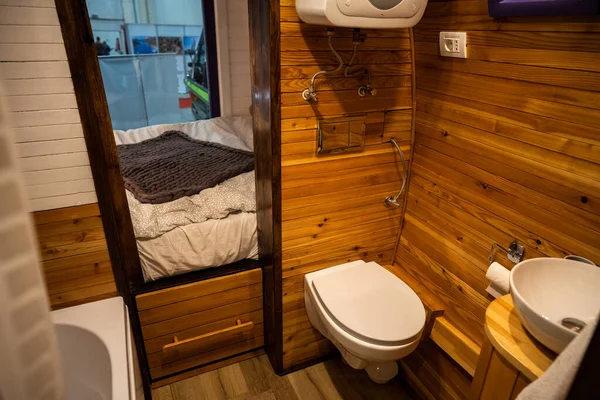 Camper van bathroom interior with toilet, sink and wooden walls.