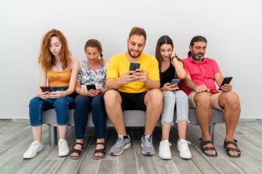 Bir grup arkadaş kanepede oturup cep telefonlarına bakıyorlar. Teknoloji bağımlılığı kavramı.