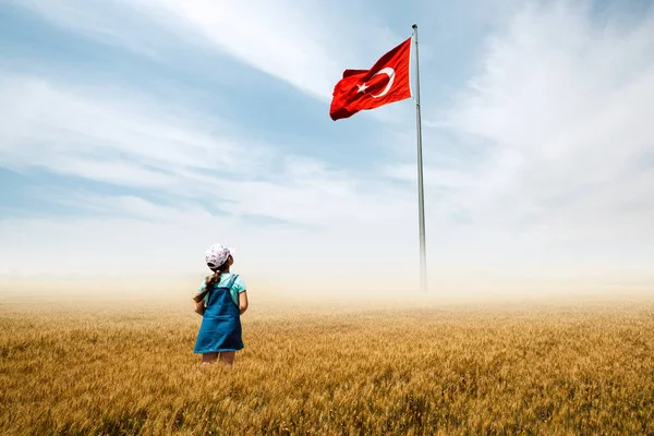 Imádnivaló kislány egy ködös mezőn van, és csodálatosan néz a török nemzeti zászlóra.. — Stock Fotó