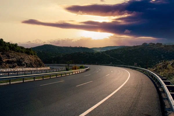 Пустая кривая асфальтовая дорога с прекрасным закатом — стоковое фото