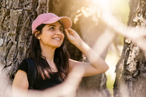 Mujer joven con sombrero deportivo rosa sonriendo en la naturaleza. — Foto de Stock